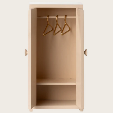 Rosa Schrank mit drei Kleiderbügeln
